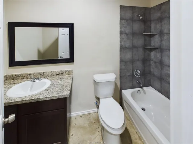 a bathroom with a granite countertop toilet sink and mirror