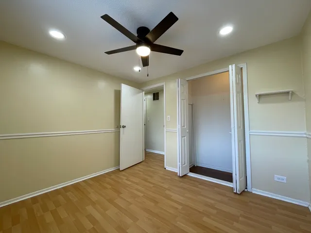 an empty room with wooden floor and a ceiling fan