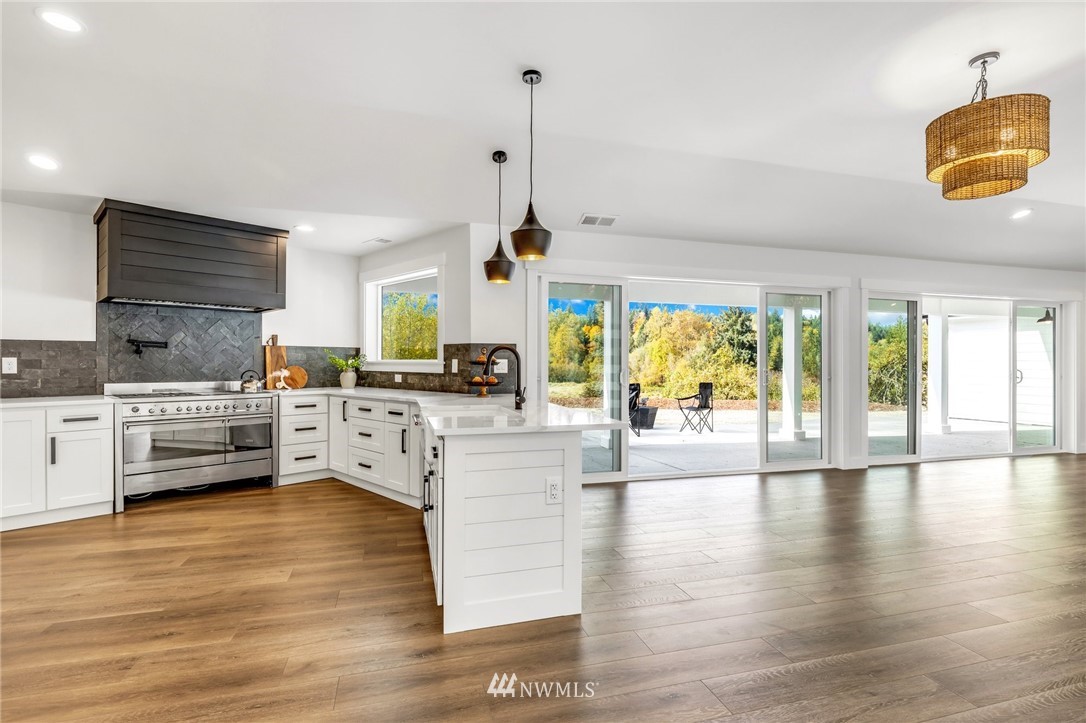 3222 Creswell Road Snohomish, WA 98290 - Photo 15 of 36 a kitchen with stainless steel appliances kitchen island granite countertop a stove a sink dishwasher and a dining table with wooden floor