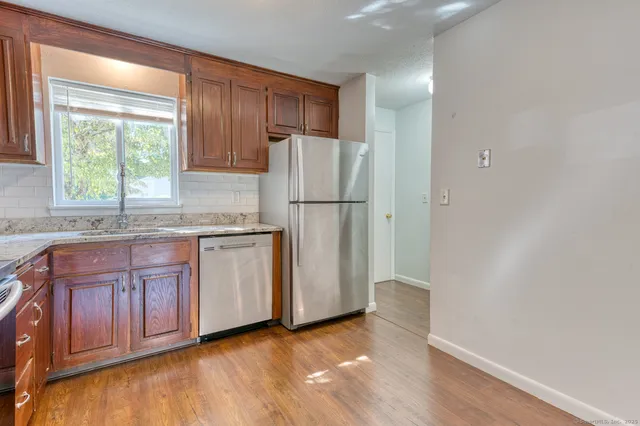 a kitchen with granite countertop a refrigerator sink and cabinets