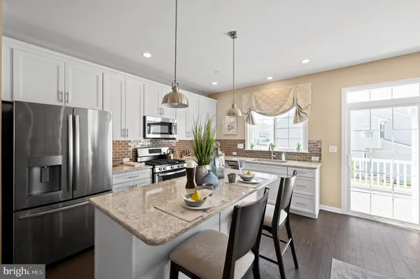 a kitchen with stainless steel appliances granite countertop a refrigerator a kitchen island a stove a dining table and chairs