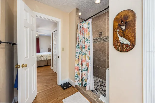 a view of a hallway with wooden floor and a bathroom