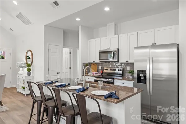 a kitchen with granite countertop a refrigerator a stove a sink cabinets and a dining table