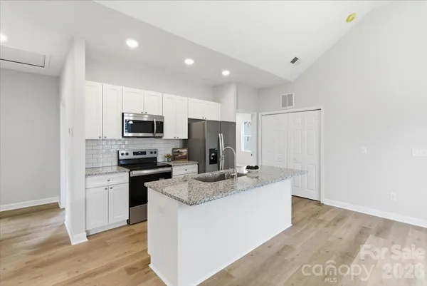 a kitchen with kitchen island granite countertop stainless steel appliances a sink a stove a microwave a center island and cabinets