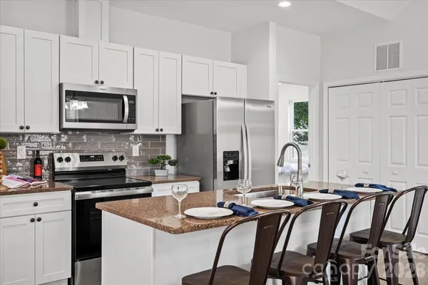 a kitchen with stainless steel appliances granite countertop a stove a sink a dining table and chairs