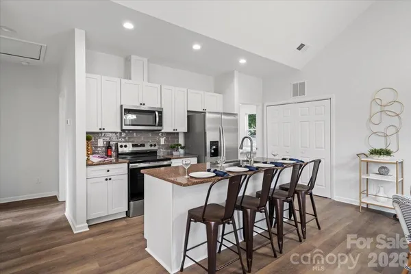 a kitchen with stainless steel appliances a table chairs microwave and refrigerator