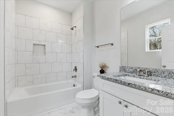 a bathroom with a granite countertop sink a toilet and bathtub