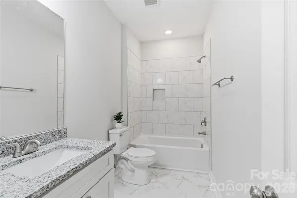 a bathroom with a granite countertop sink a toilet and shower