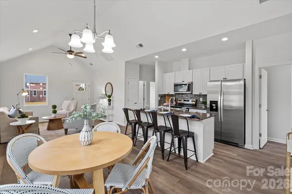 a kitchen with stainless steel appliances kitchen island granite countertop a dining table chairs and a refrigerator