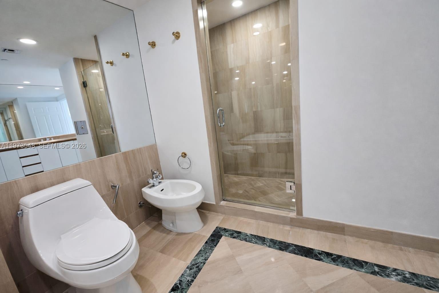 1643 Brickell Avenue, Unit 903 Miami, FL 33129 - Photo 17 of 18 a bathroom with a toilet a sink and a mirror