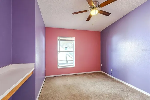 an empty room with a window and a fan