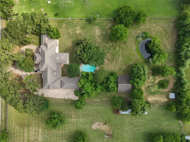an aerial view of residential house with outdoor space and trees all around