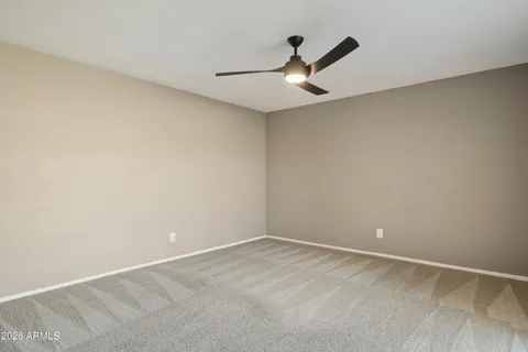 an empty room with a ceiling fan and carpet