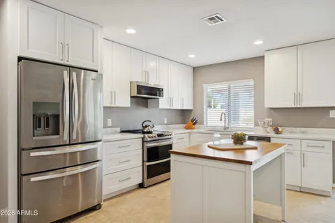 a kitchen with white cabinets and stainless steel appliances