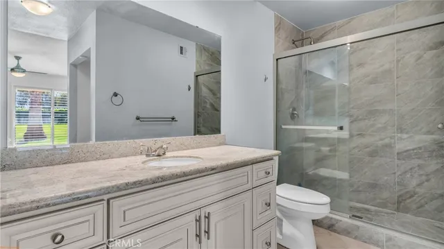 a bathroom with a granite countertop sink a toilet and shower