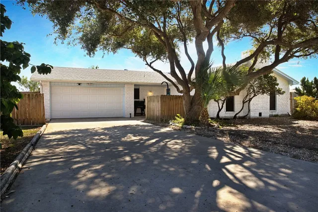 a view of a white house next to a road and yard