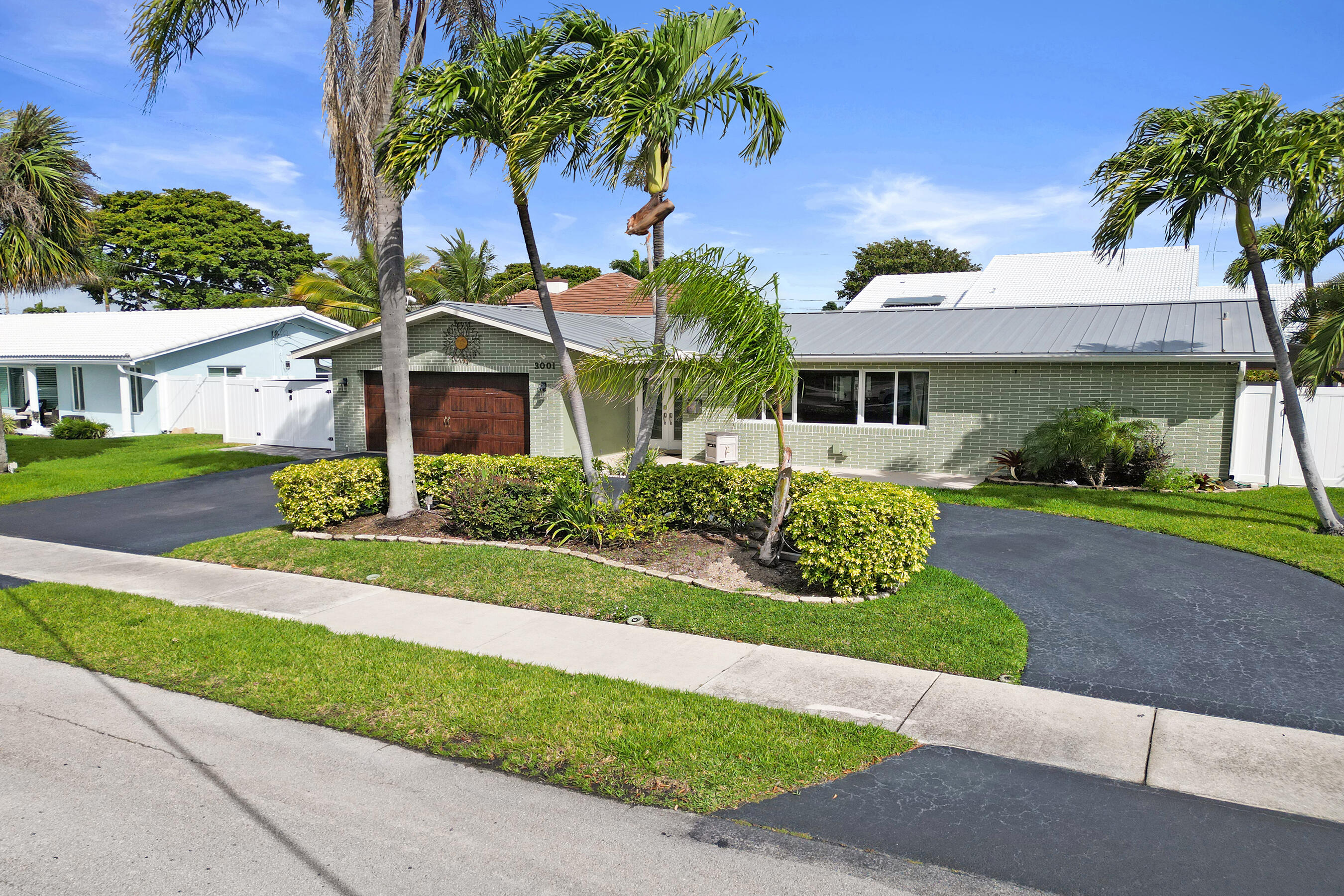 3001 Northeast 45th Street Lighthouse Point, FL 33064 - Photo 2 of 67 a front view of a house with a garden and palm trees