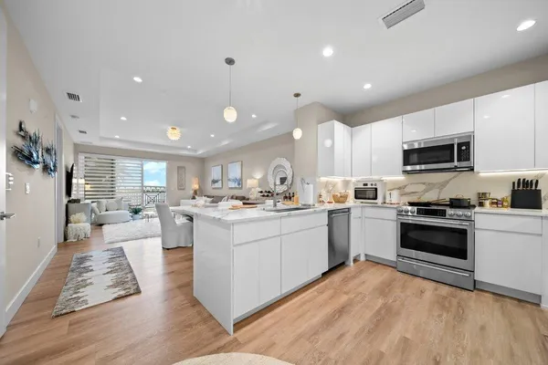 a large white kitchen with kitchen island a sink a stove a center island and a window