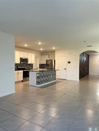 a view of kitchen with kitchen island granite countertop a stove and a sink