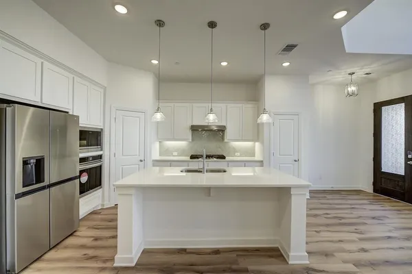 a view of kitchen with kitchen island white cabinets and stainless steel appliances