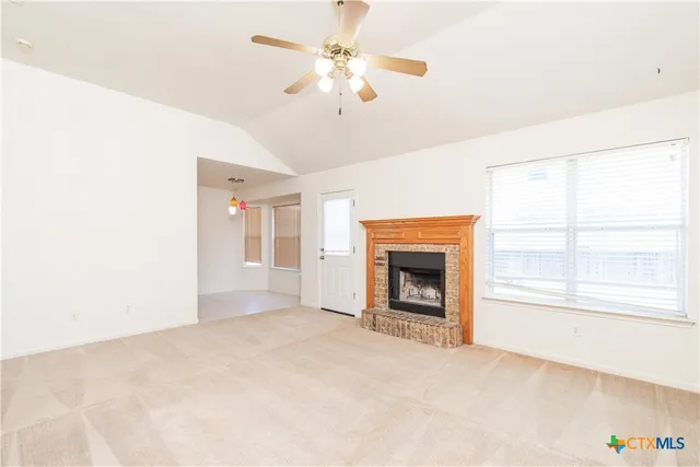 an empty room with chandelier fan and windows