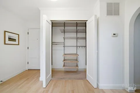 an empty room with wooden floor closet and windows
