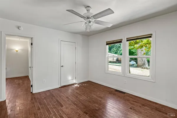a view of empty room with wooden floor and fan
