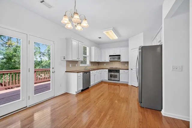 a kitchen with stainless steel appliances granite countertop a refrigerator a sink dishwasher a stove and white countertops with wooden floor