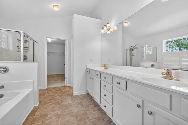 a spacious bathroom with double sink a large mirror and a bathtub