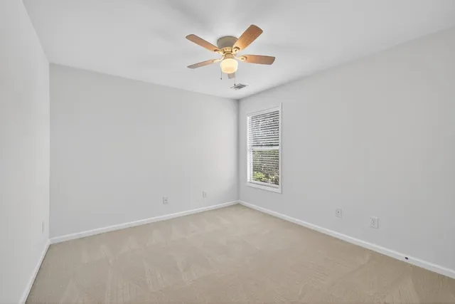 an empty room with window and ceiling fan