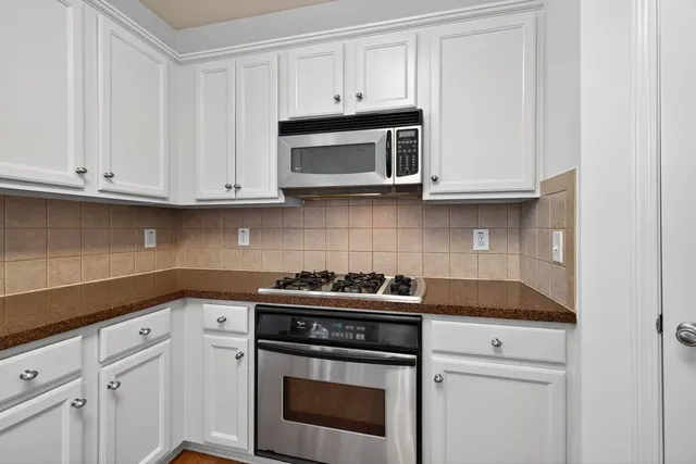 a kitchen with granite countertop white cabinets and a stove a oven with white countertops