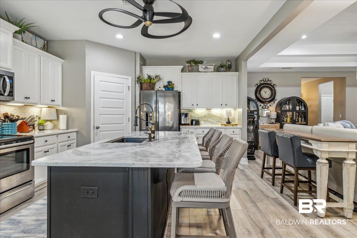 7022 Rocky Rd Loop Gulf Shores, AL 36542 - Photo 15 of 59 Kitchen with appliances with stainless steel finishes, ceiling fan, a breakfast bar area, white cabinetry, and backsplash