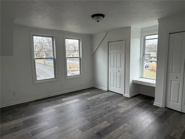 a view of an empty room with wooden floor and windows