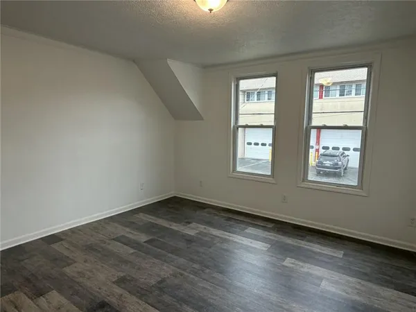 a view of an empty room with wooden floor and windows