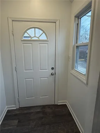 an empty room with wooden floor cabinet and window