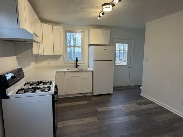 a kitchen with a refrigerator a stove top oven a sink and cabinets