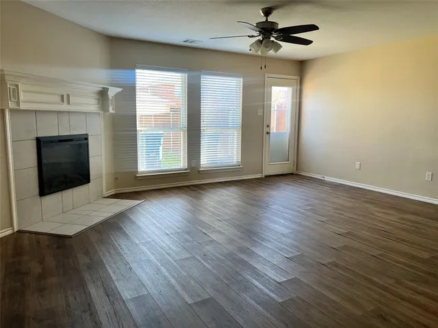 a view of a livingroom with wooden floor a ceiling fan and windows