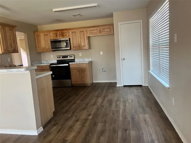 a kitchen with a refrigerator stove and wooden floor