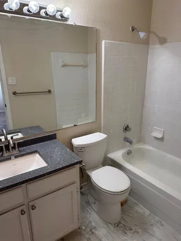 a bathroom with a granite countertop toilet a sink and bathtub