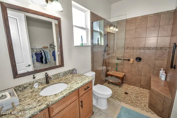a bathroom with a granite countertop sink a mirror and a toilet