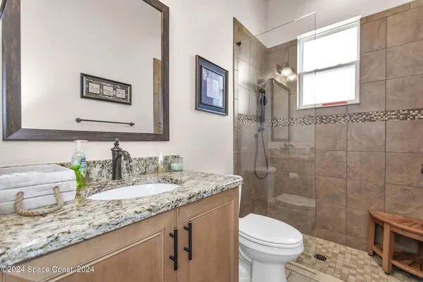 a bathroom with a granite countertop toilet sink and mirror