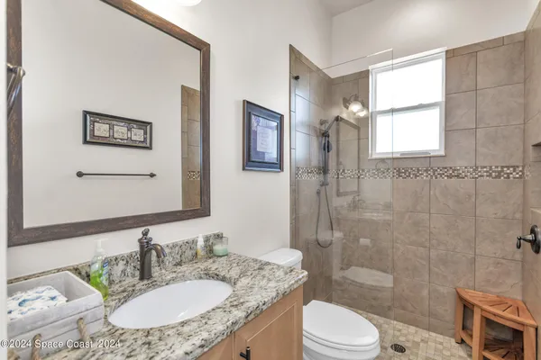a bathroom with a granite countertop sink toilet a mirror and shower