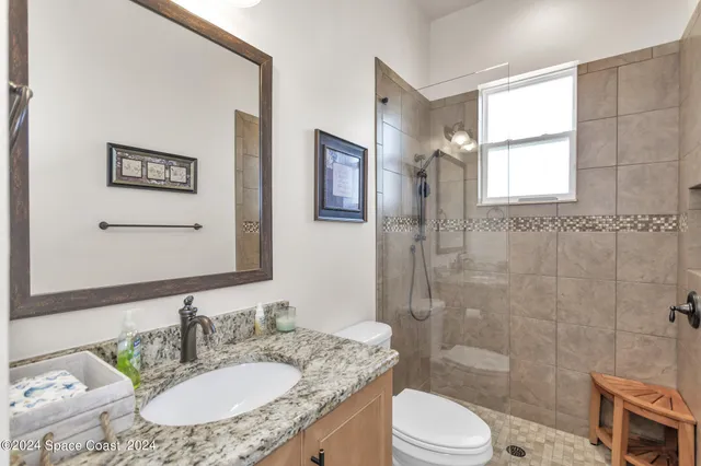 a bathroom with a granite countertop sink toilet a mirror and shower