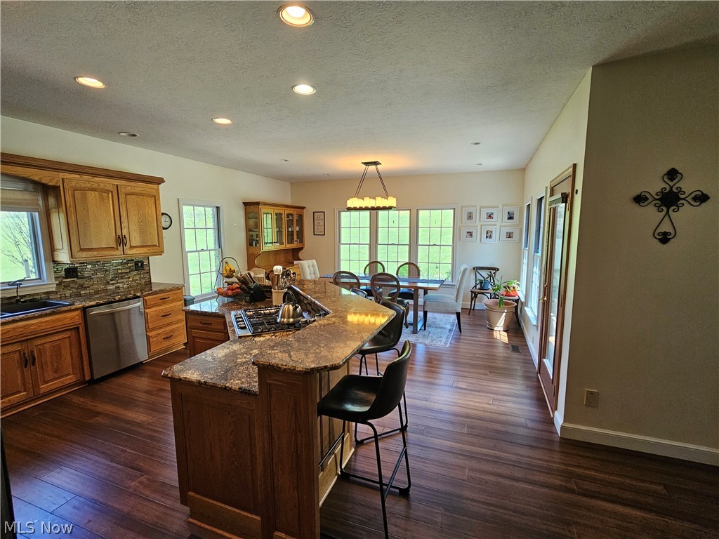 2363 Tabor Ridge Road Northeast New Philadelphia, OH 44663 - Photo 20 of 42 Open-concept kitchen and dining area featuring rich wood-finish flooring, recessed lighting, and a kitchen island with stone countertops and a built-in cooktop