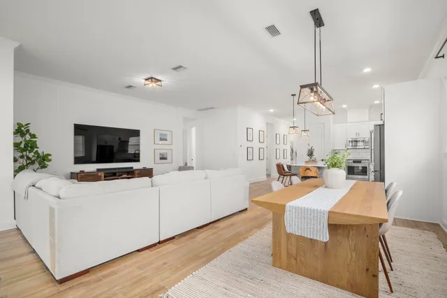 a living room with furniture a flat screen tv and kitchen view