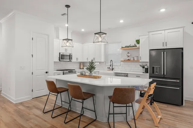 a kitchen with stainless steel appliances granite countertop a sink a stove a refrigerator and island with wooden floor