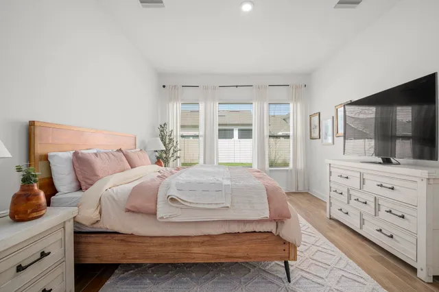 a bedroom with a large bed and a flat tv screen on dresser