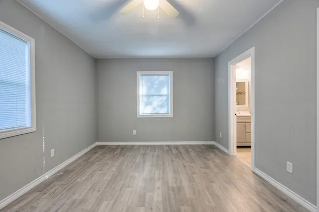an empty room with wooden floor and windows