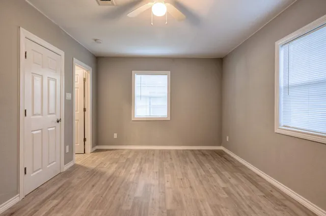 an empty room with wooden floor and windows