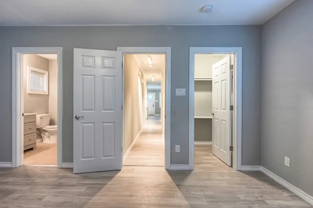 a view of a hallway with wooden floor and a living room